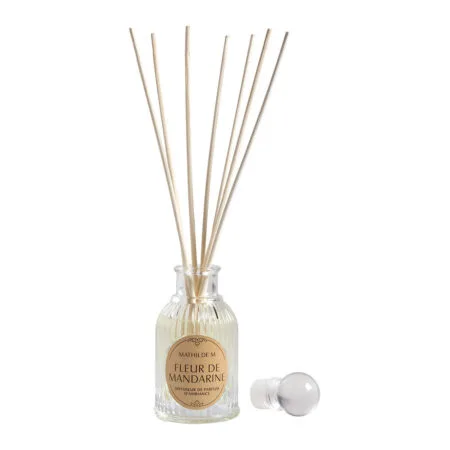 Diffuseur de parfum d’ambiance Mathilde M – Fleur de mandarine en flacon élégant avec tiges en rotin, posé dans un intérieur raffiné