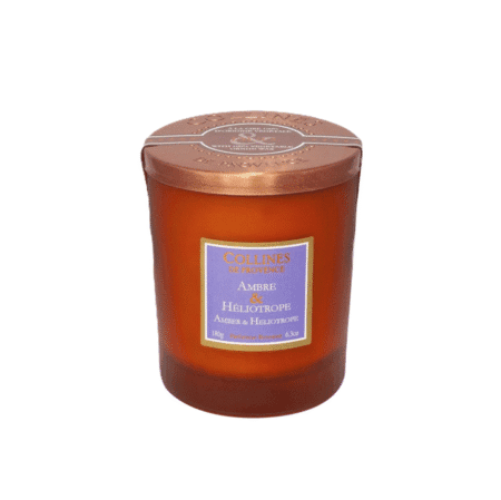 Bougie parfumée 180g Colline de Provence, senteur Ambre Héliotrope, dans un pot élégant posé sur une table boisée et chaleureuse.
