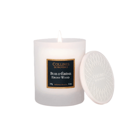 Bougie parfumée Colline de Provence 180g senteur Bois d’Ébène, dans un pot sobre et chic, posée sur une table en bois brut avec une lueur chaleureuse.