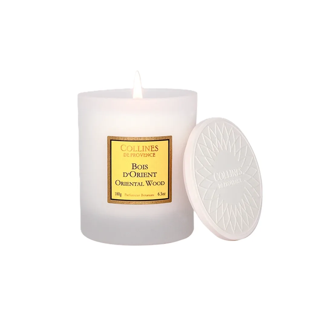 Bougie parfumée 180g Colline de Provence Bois d’Orient, dans un pot élégant, diffusant une lueur chaleureuse et une ambiance exotique.